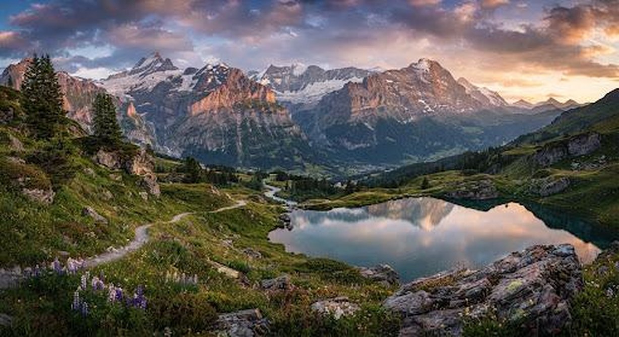 A still alpine lake mirroring snow-dusted peaks at dusk