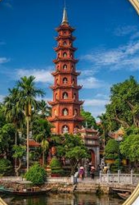 Tran Quoc Pagoda rising above palm trees beside a lake in Hanoi, Vietnam
